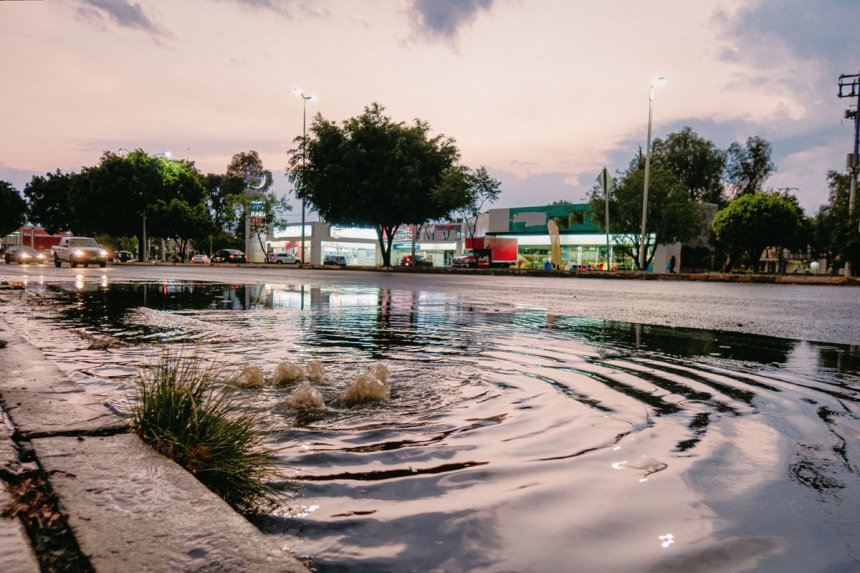 A partially flooded street as stormwater bubbles out of the drain.
