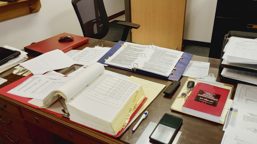 Highway superintendent's desk covered with open binders and files.